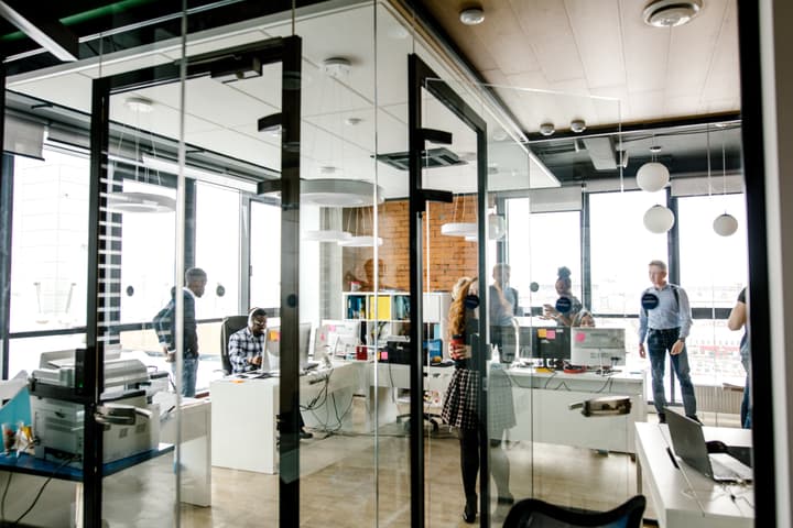 Modern bright small office with glass walls, glass door, panorama window and stylish lamps