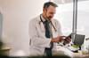 White male doctor uses ipad in a healthcare office setting.