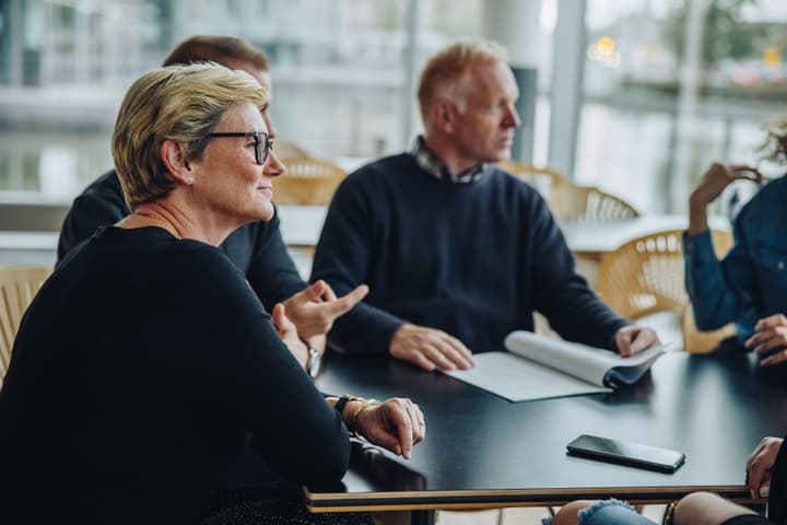 A senior businesswoman sits at a table during a business meeting.