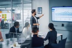 Businessman Leads Meeting with Data on Screen